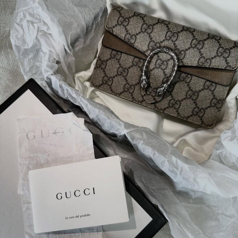 Gucci handbag with branded paper and packaging on a light background